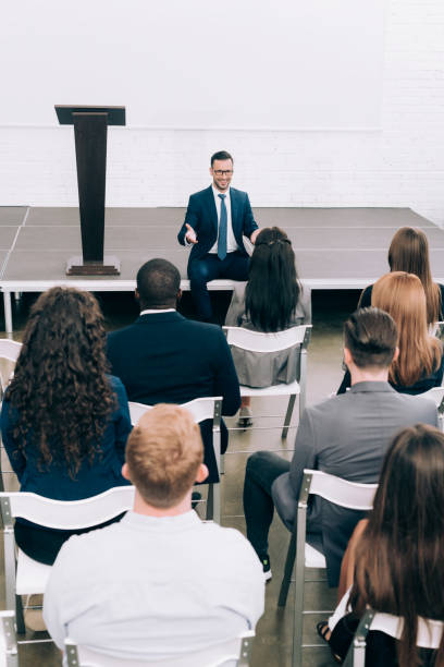 istock high angle view speaker sitting on stage during seminar in conference hall 1057330124