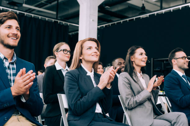 smiling multiethnic businesspeople applauding during business seminar in conference hall smiling multiethnic businesspeople applauding during business seminar in conference hall applaus stock pictures, royalty-free photos & images