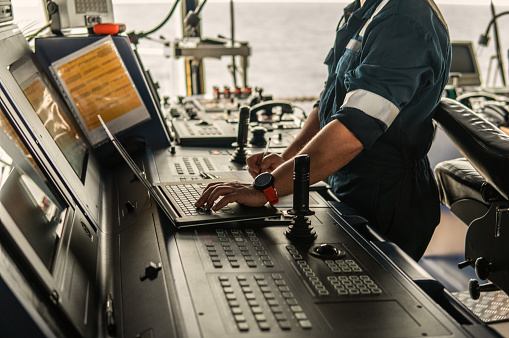 Marine navigational officer or technician is using laptop or notebook at sea. Job at sea