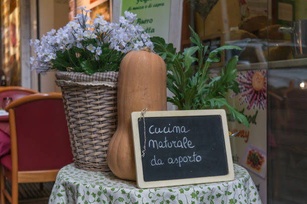 istock Flowered Composition with a Pumpkin and a Blackboard with the sentence natural takeaway cuisine in Italian on Blur Background 1057332992