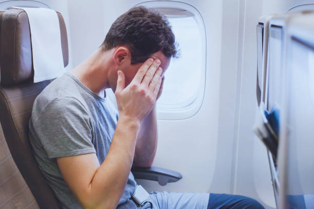 headache in the airplane, man passenger afraid and feeling bad during flight, fear stock photo