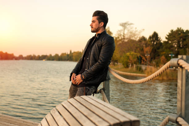 istock Handsome young man standing outside watching the sunset at the river 1057336848