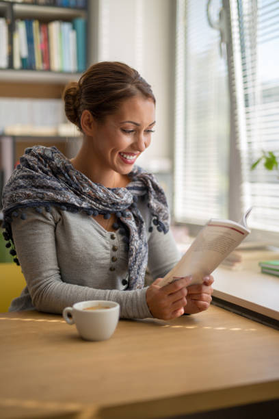 istock Beautiful young woman reading a book in a library 1057343808