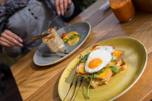 istock Closeup of egg breakfast sandwich with womens hands blurry in background 1057343864