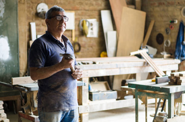 Portrait of senior carpenter. Standing in his workshop. stock photo
