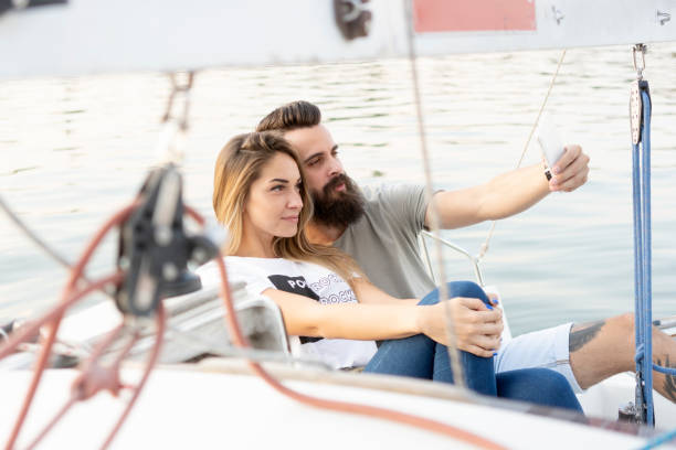 魅力的なカップルを緩和、写真を撮って、ヨットにスマート フォンを使用して ストックフォト