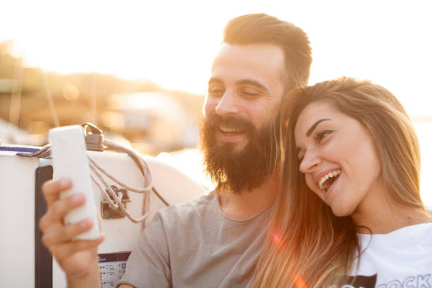 istock Attractive couple relaxes, taking photos and using a smartphone on a sailboat 1057355536