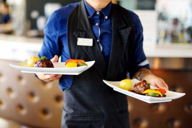 いくつかのお祭りのイベントの上に肉料理と 2 つのプレートを運ぶウェイター - serving food restaurant chicken ストックフォトと画像