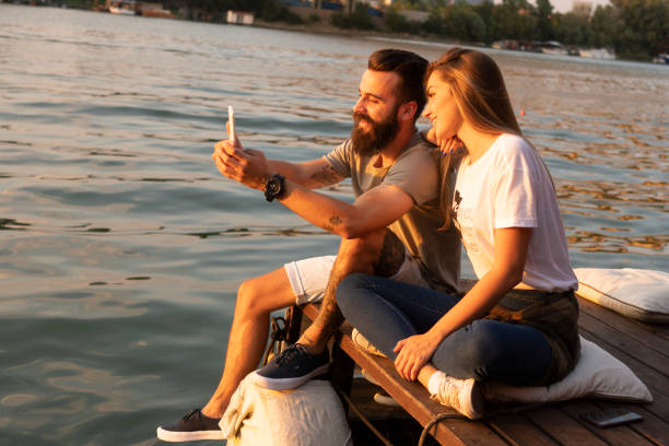 istock Young couple taking selfie with smartphone on river 1057373090
