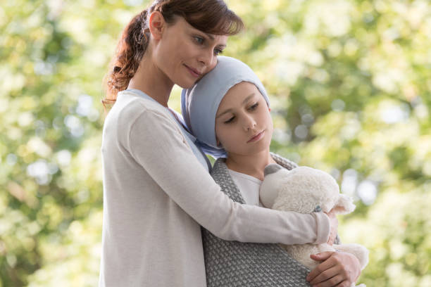 Mother hugging sad daughter with cancer