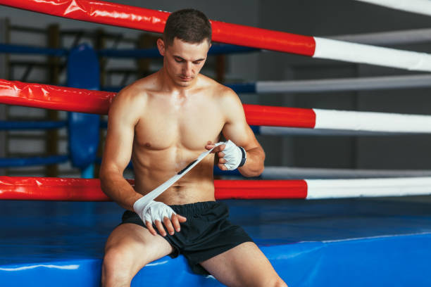 istock Boxer man is wrapping hands with boxing wraps 1057383048