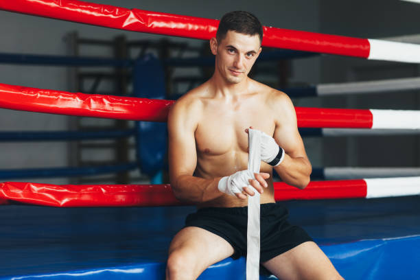 istock Handsome boxer bandages his hand behind ring 1057383054