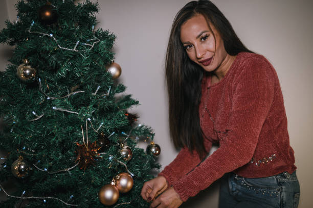 istock Charming young woman decorating Christmas tree during holiday 1057400556