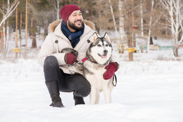 istock Smiling Asian Man with Dog in Winter 1057403332