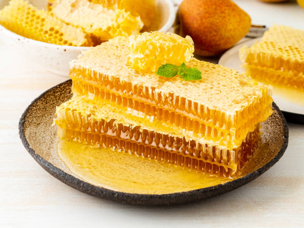 istock honey in honeycomb, close-up, on brown ceramic plate, on white wooden rustic table, side view 1057406672