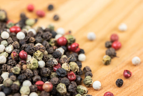 Different types of peppercorns - black, white, pink and green pepe verde - on white. Top view. Copy space.