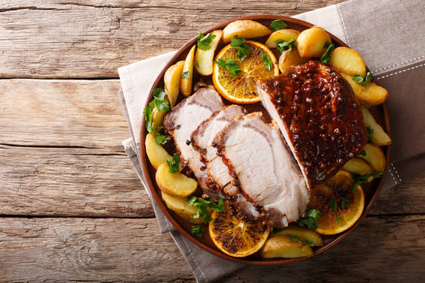 Christmas baked pork with potatoes, oranges and apples. horizontal top view from above Christmas baked pork with potatoes, oranges and apples close-up on a plate. horizontal top view from above loin stock pictures, royalty-free photos & images