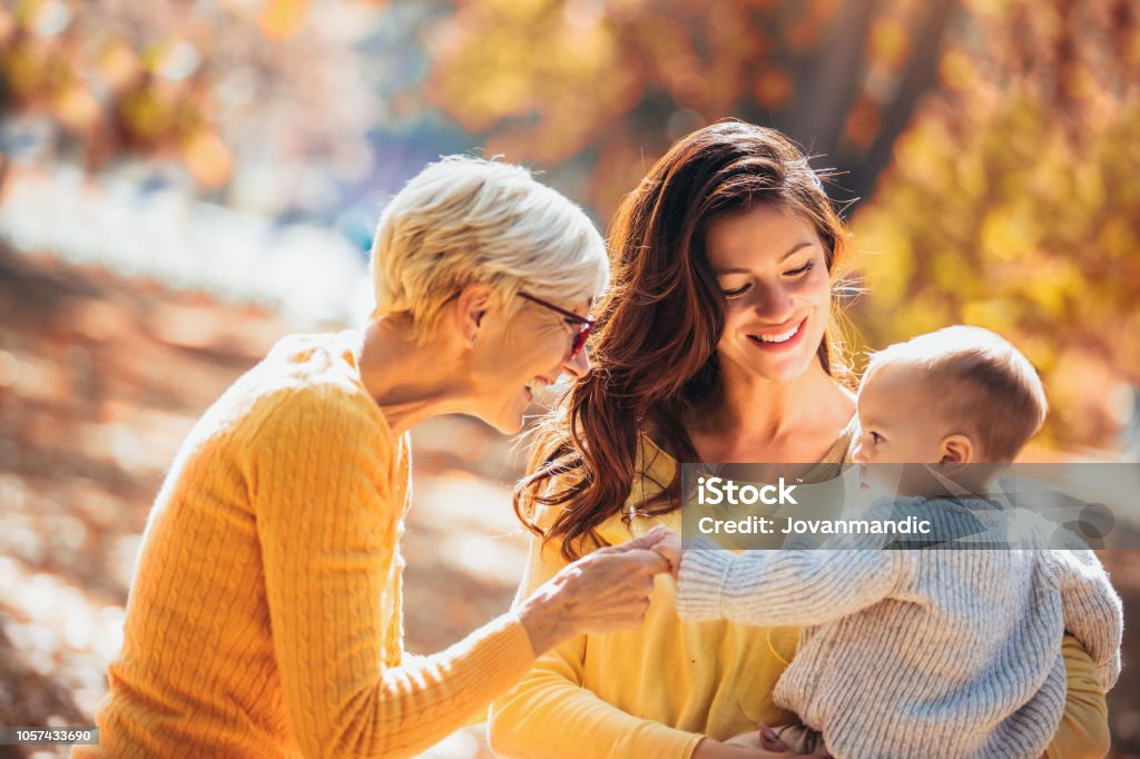 Grand-mère et la mère sourit à bébé en automne parc. - Photo de Grand-mère libre de droits