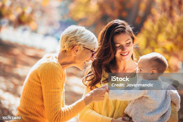 Grandmother And Mother Smiling At Baby In Autumn Park Stock Photo - Download Image Now