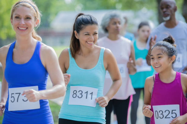 母と娘の競合他社の多様なグループでマラソンを実行します。 - marathon running group of people jogging ストックフォトと画像