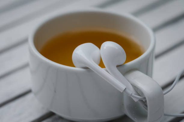 casque blanc sur le bord d’une tasse de thé - at the edge of audio photos et images de collection