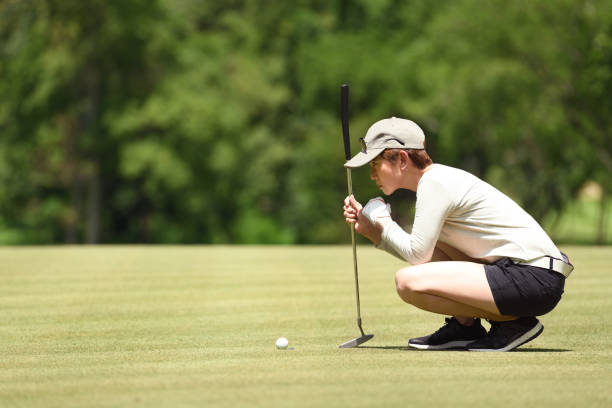 Woman golfer check line for putting a golf ball on green grass