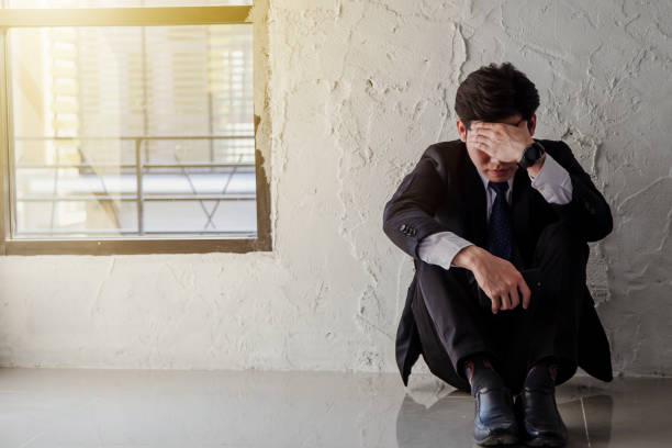 istock Young asian businessman sitting by the window feel stressed and depressed from work. 1057449374