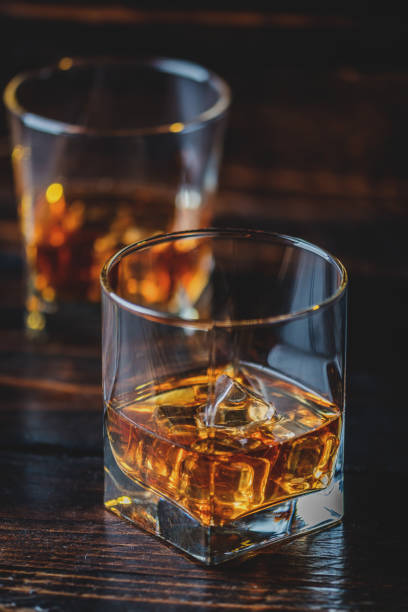 Whisky, whiskey or bourbon Alcohol drink whisky, whiskey or bourbon with ice cubes on dark wood table glass of bourbon stock pictures, royalty-free photos & images
