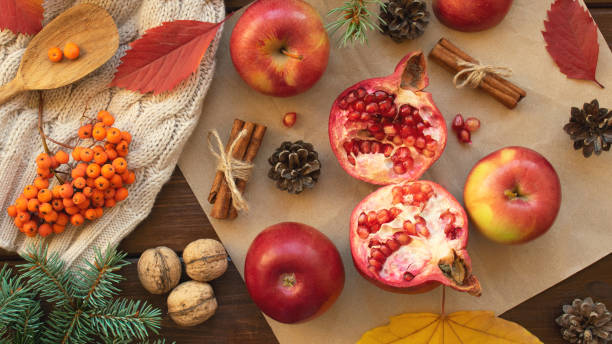 istock Apples, pomegranate, cinnamon, cones, walnuts, fallen leaves on a wooden background. Autumn composition. Top view. 1057471666