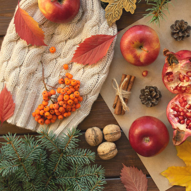 istock Apples, pomegranate, cinnamon, cones, walnuts, fallen leaves on a wooden background. Autumn composition. Top view. 1057471696