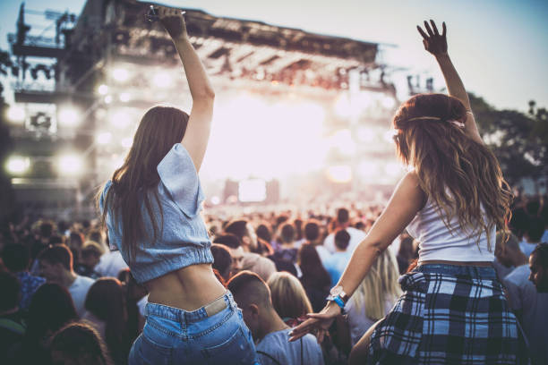 Back view of female friends having fun on a music concert. Rear view of carefree female friends dancing on a music festival. music festival stock pictures, royalty-free photos & images