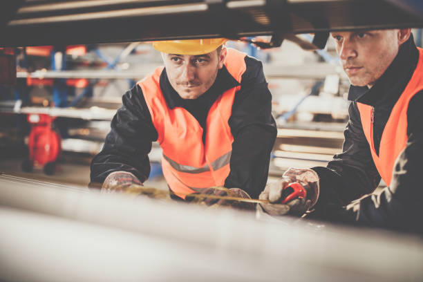 istock Metal workers cooperating while measuring iron in aluminum mill. 1057485390