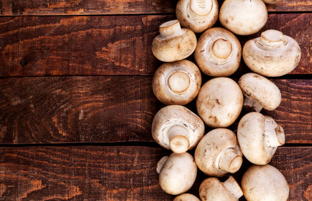 istock Fresh champignon mushrooms on wooden table, top view. Copy space 1057485746