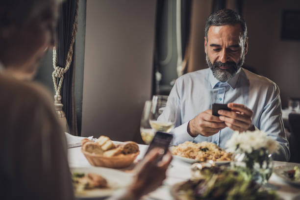 istock Smiling senior man using cell phone on a lunch with his wife. 1057489840