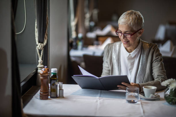 istock Happy mature woman reading Menu in a restaurant. 1057489962