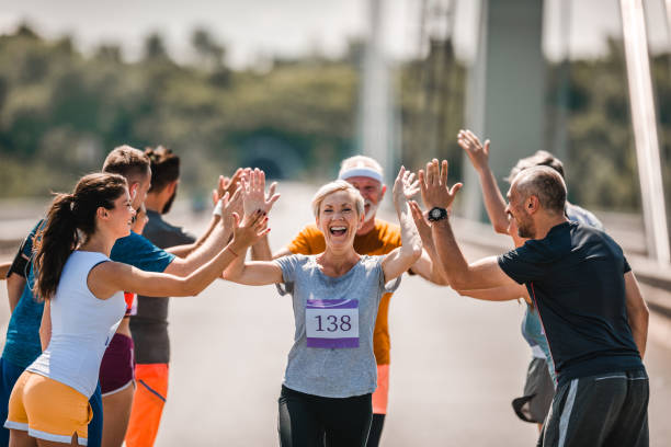 istock Cheerful senior runner greeting her supporters during marathon race. 1057492808
