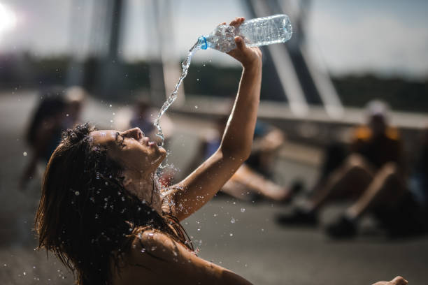 istock Exhausted athlete pouring water onto herself on a break from marathon race. 1057494506