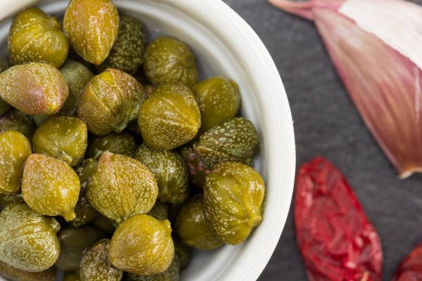 Capers pickled in brine The caper is a vegetable ingredient of Mediterranean cuisine with an intense flavor and aroma. caper stock pictures, royalty-free photos & images