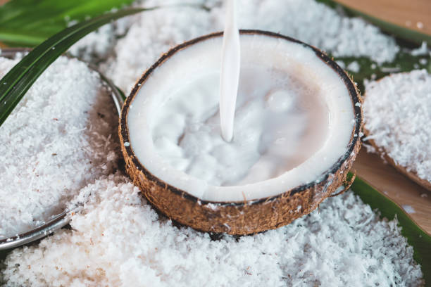 pouring fresh coconut milk in bowl and coconut fruit ingredient pouring fresh coconut milk and coconut fruit ingredient on wooden table coconut milk photos stock pictures, royalty-free photos & images