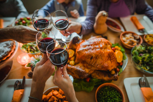 Cheers to this great Thanksgiving dinner! Group of unrecognizable people toasting with wine during Thanksgiving dinner at dining table. happy thanksgiving stock pictures, royalty-free photos & images