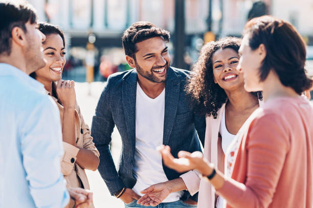Friendly chat Multi-ethnic group of smiling young people talking outdoors in the city indian woman laughing stock pictures, royalty-free photos & images