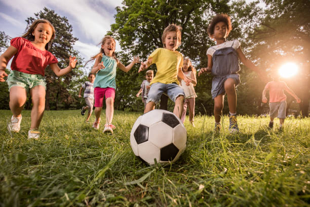 istock Below view of playful children having fun while playing soccer in nature. 1057500450