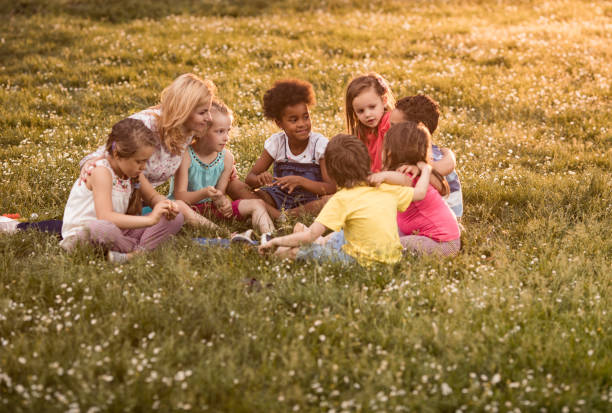 istock Smiling teacher having a class with school kids in the park. 1057500694