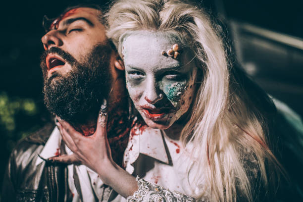 Undead zombie woman biting young man Woman dressed as witch biting man at night. Zombie concept male vampire biting his victim stock pictures, royalty-free photos & images