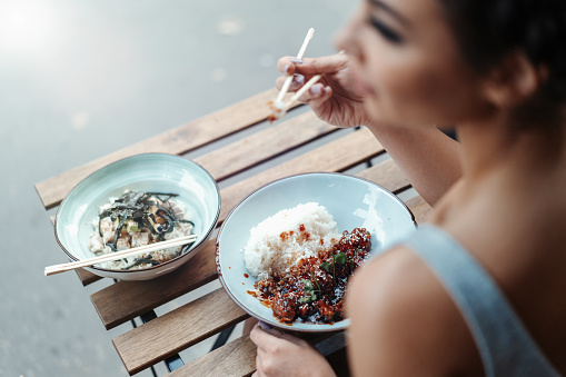 Beautiful woman eating chicken with rice in street cafe of chinese food.
