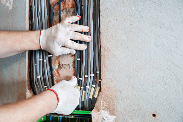 An electrician is installing electric wires in a switching fuse box.