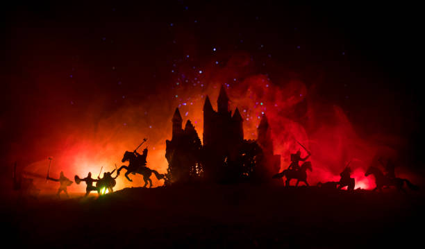 istock Medieval battle scene with cavalry and infantry. Silhouettes of figures as separate objects, fight between warriors on dark toned foggy background with medieval castle. Night scene. Selective focus 1057527348
