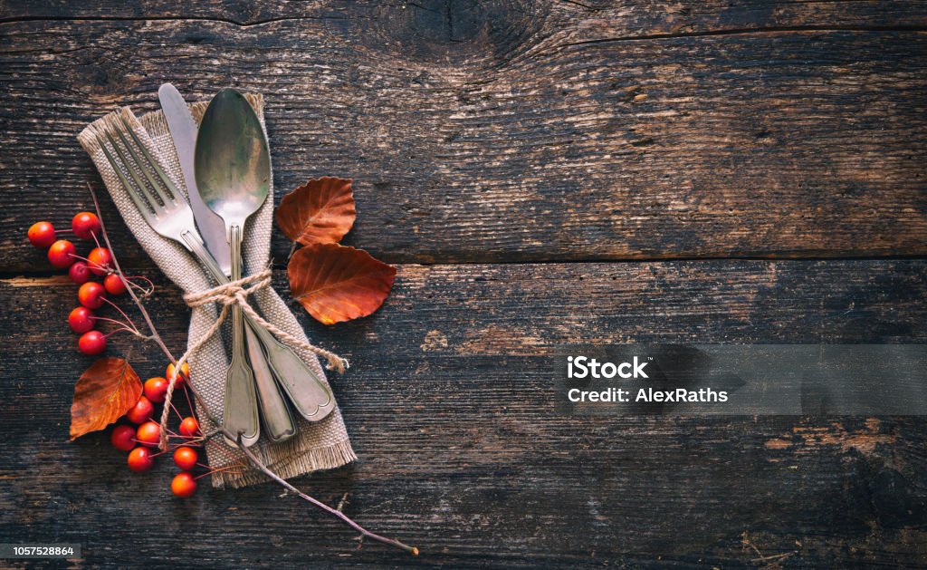 Autumn background with vintage place setting on old wooden table Autumn background from fallen leaves and fruits with vintage place setting on old wooden table. Thanksgiving day concept Thanksgiving - Holiday Stock Photo