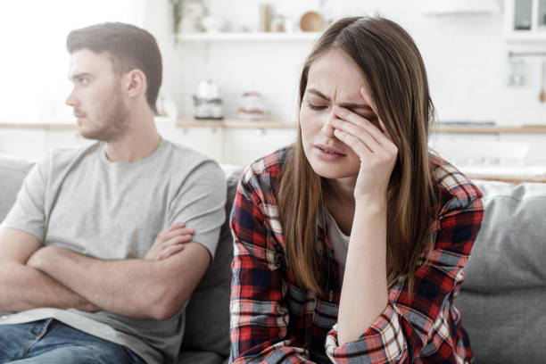 Couple conflict. Stressed crying female sitting on couch with abusive husband after quarrel, ready to divorce Couple conflict. Stressed crying female sitting on couch with abusive husband after quarrel, ready to divorce relationship difficulties stock pictures, royalty-free photos & images