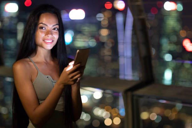 istock Smiling woman text messaging outdoors, at night 1057550056